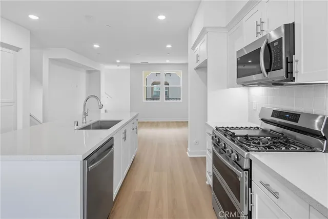 a kitchen with stainless steel appliances granite countertop a sink a stove and a refrigerator