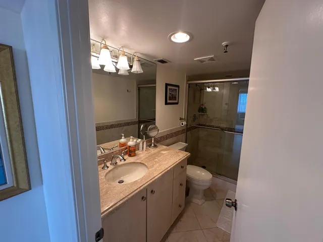 a bathroom with a sink a toilet a mirror and shower