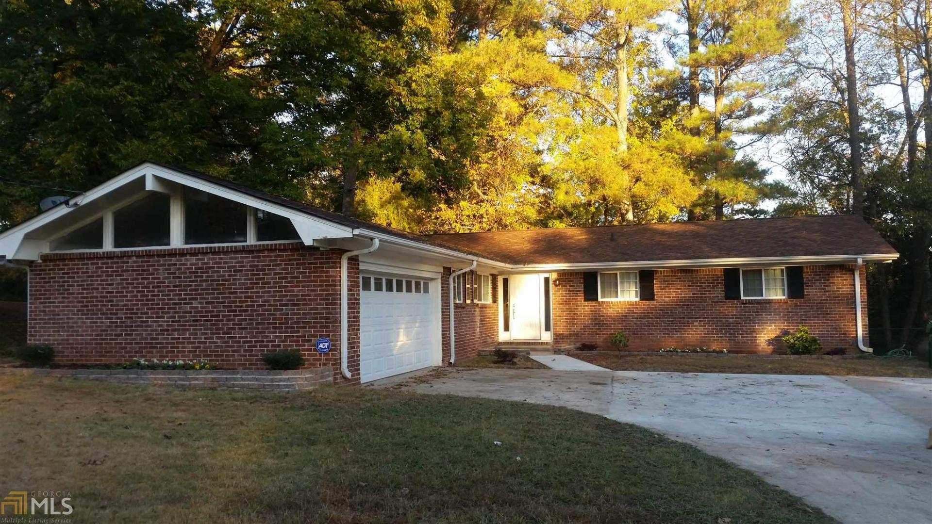 a front view of house with yard and trees in the background