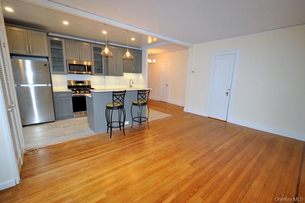 69 Harney Road, Unit 3A Scarsdale, NY 10583 - Photo 6 of 22 Renovated Kitchen with center Island, pendent lighting, Granite Counters, Stainless Steel Appliance including a dishwasher, range, microwave and refrigerator. The wall separating the eat-in-kitchen and living room have been removed and a center Island installed with electric and USB outlets installed to create an open concept.