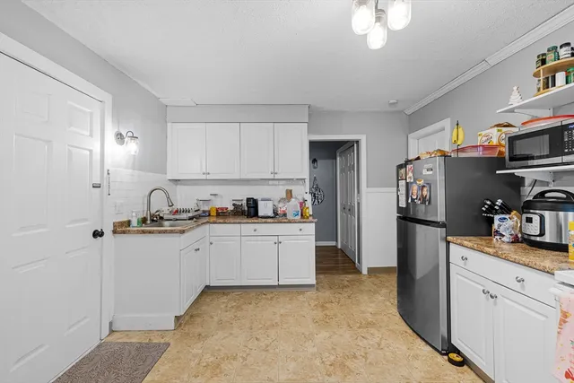 a kitchen with stainless steel appliances granite countertop a refrigerator sink and white cabinets