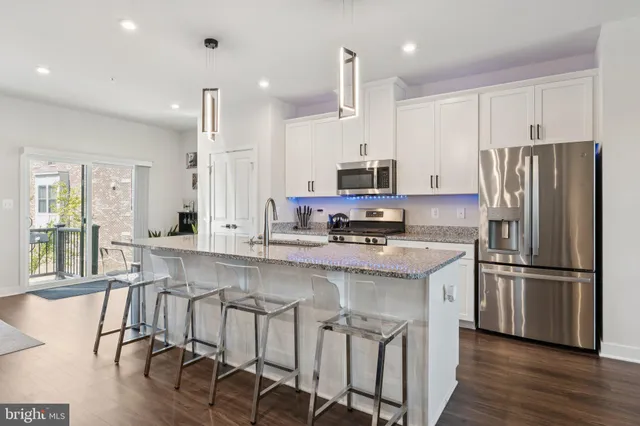 a large white kitchen with a stove a sink a dining table and chairs