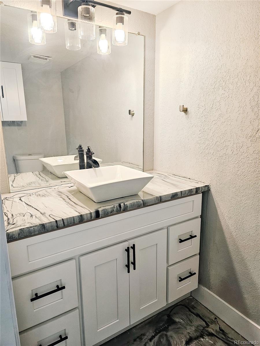 4716 Freeport Way Denver, CO 80239 - Photo 25 of 29 a bathroom with a granite countertop sink and white cabinets