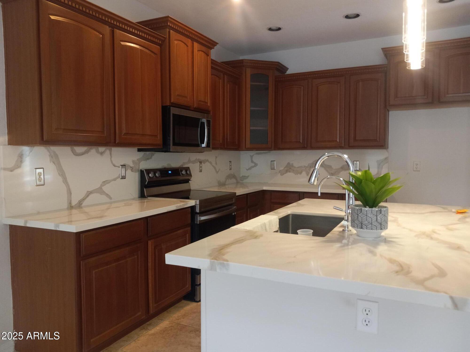 3947 West Roundabout Circle Chandler, AZ 85226 - Photo 13 of 32 a kitchen with stainless steel appliances kitchen island granite countertop a sink a stove a microwave and wooden cabinets
