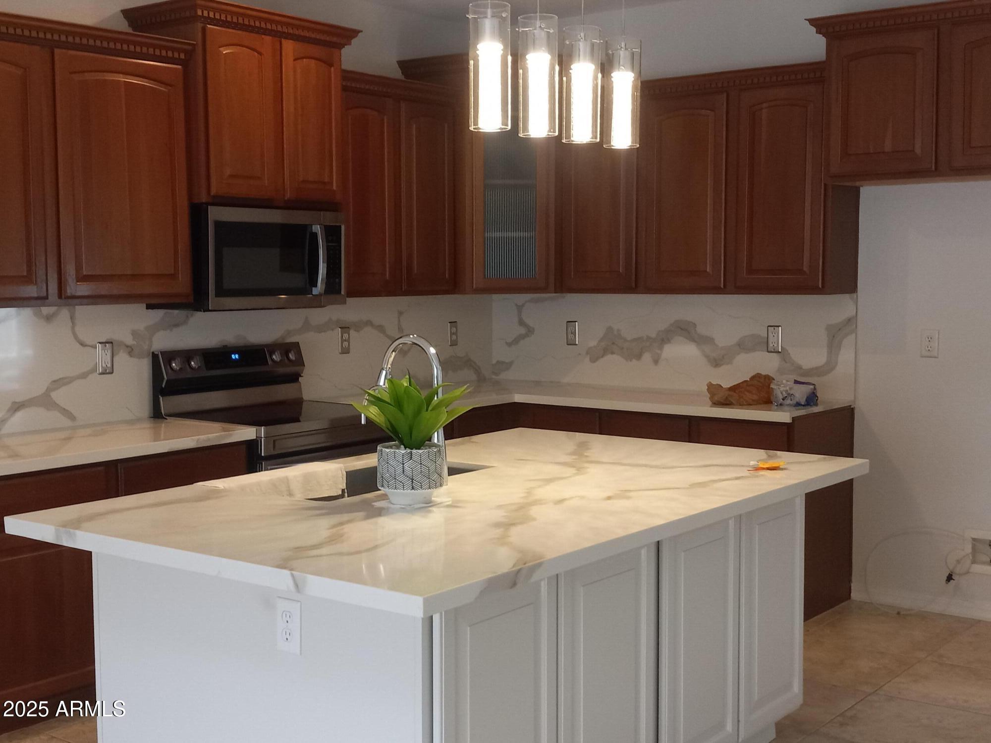 3947 West Roundabout Circle Chandler, AZ 85226 - Photo 15 of 32 a kitchen with stainless steel appliances granite countertop a sink a stove a microwave and wooden cabinets