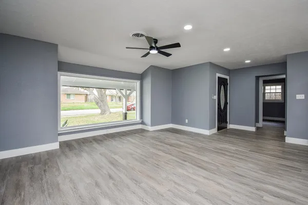 a view of an empty room with a window and wooden floor