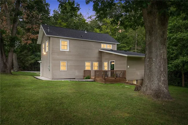 a backyard of a house with table and chairs and large tree