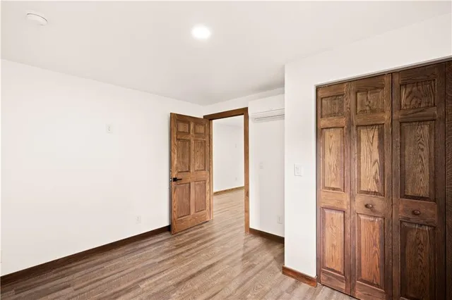 an empty room with wooden floor and closet area