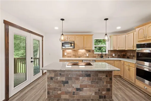 a kitchen with kitchen island granite countertop a stove a sink and white cabinets with wooden floor