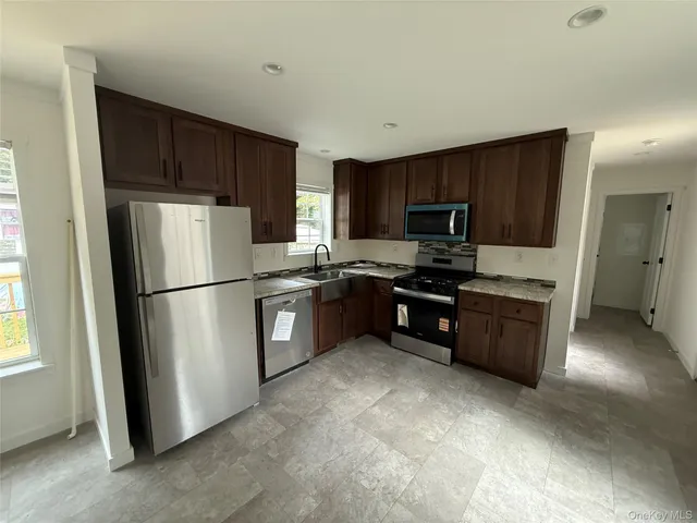 a kitchen with stainless steel appliances granite countertop a refrigerator stove a sink dishwasher and microwave