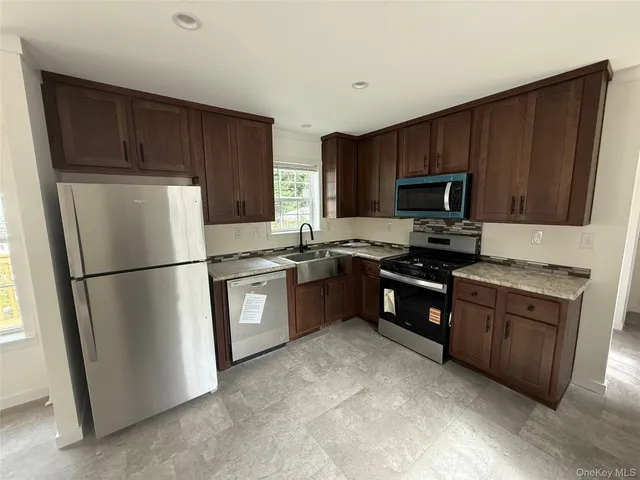 a kitchen with granite countertop a refrigerator stove and microwave