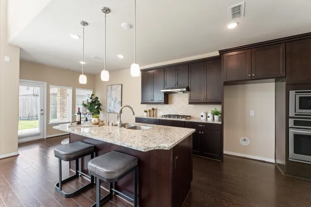 a kitchen with refrigerator a sink a counter and chairs