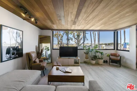 a living room with furniture flat screen tv and a large window