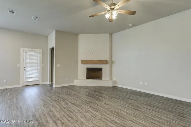 a view of an empty room with wooden floor and a fireplace
