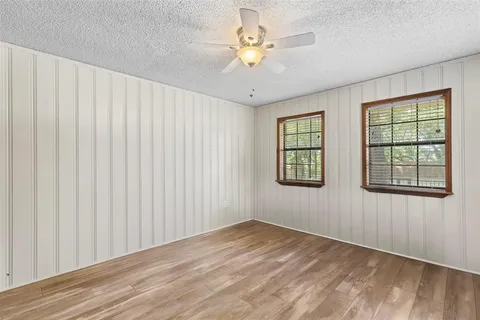 an empty room with windows and ceiling fan