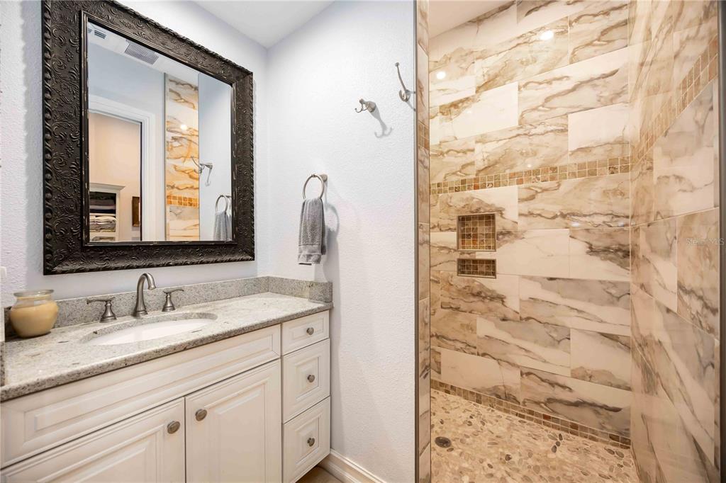 3674 Roslyn Road Venice, FL 34293 - Photo 24 of 72 a bathroom with a granite countertop sink a mirror and a shower