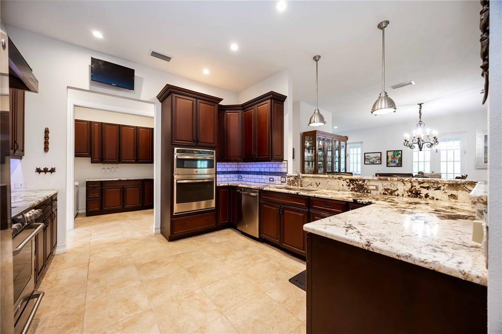 3674 Roslyn Road Venice, FL 34293 - Photo 30 of 72 a kitchen with stainless steel appliances kitchen island granite countertop a refrigerator a sink and a stove