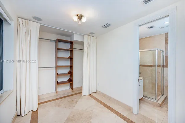 a view of a white house with a small yard plants and large tree