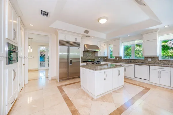 a large kitchen with stainless steel appliances kitchen island granite countertop a refrigerator and a sink