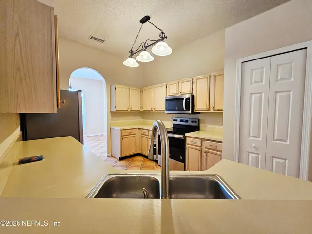 a kitchen with a refrigerator a sink and white cabinets