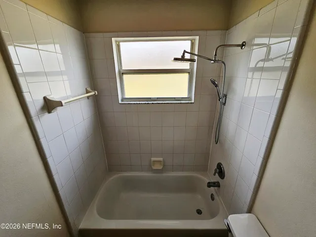 a bathroom with a tub a sink and a window