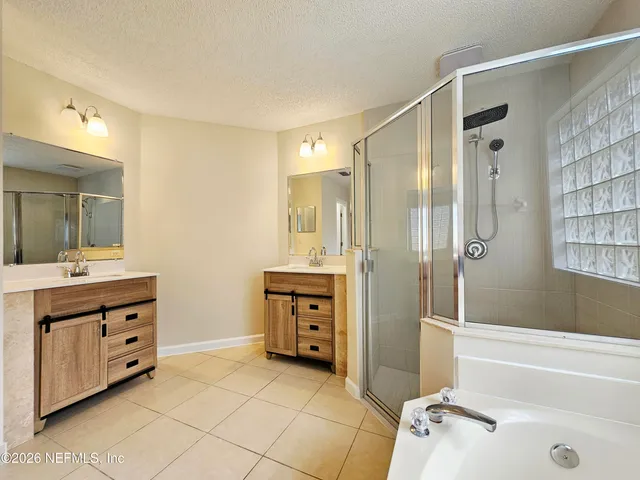 a bathroom with a double vanity sink tub mirror and shower