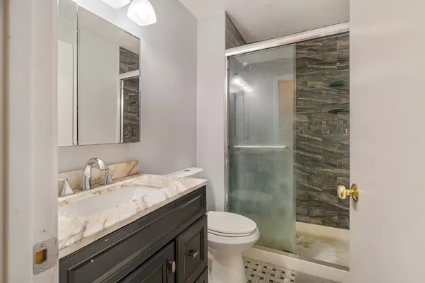 a bathroom with a granite countertop sink a toilet and shower
