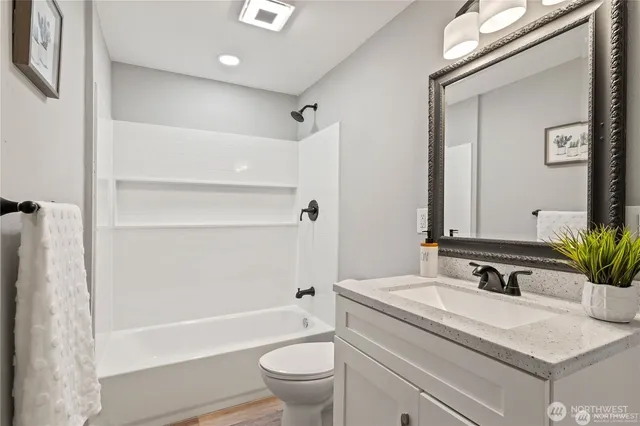 a bathroom with a granite countertop sink a toilet and shower