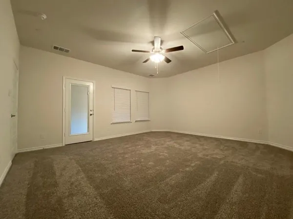 an empty room with chandelier fan and windows