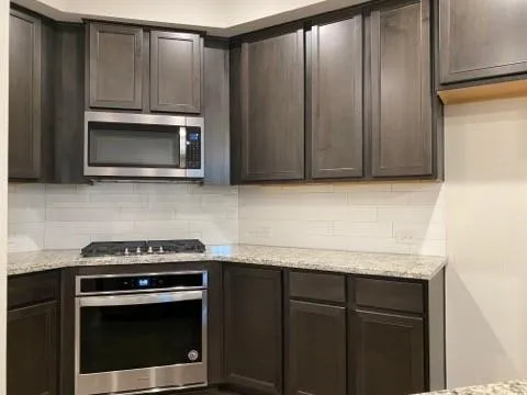 a kitchen with granite countertop white cabinets and stainless steel appliances