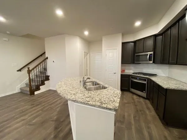 a kitchen with stainless steel appliances granite countertop a stove a sink and a refrigerator