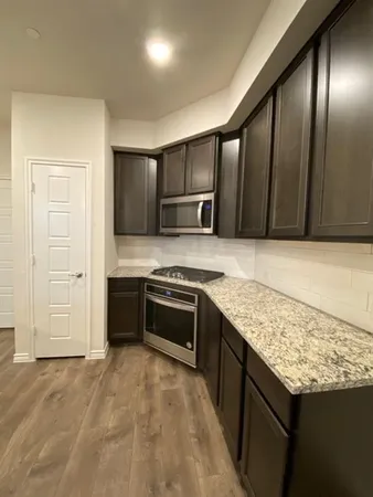 a kitchen with stainless steel appliances granite countertop a stove a sink and a refrigerator with wooden cabinets