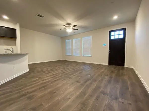 a view of an empty room with window and wooden floor