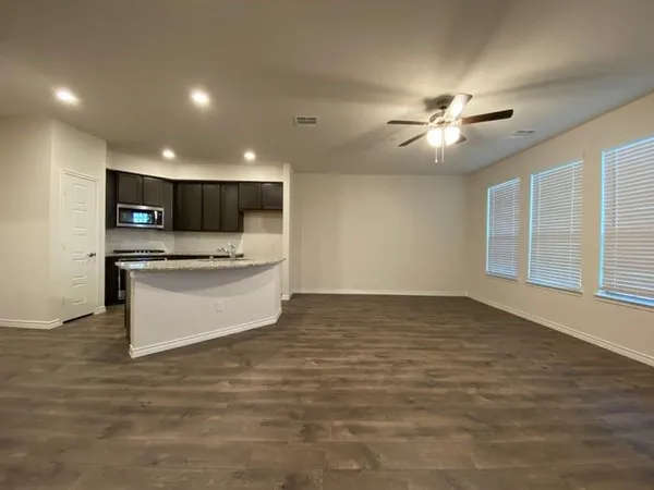 a view of kitchen with stainless steel appliances kitchen island a stove a refrigerator a oven with white cabinets and wooden floor