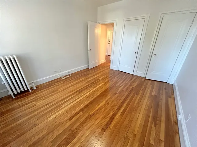 a view of an empty room with wooden floor and closet