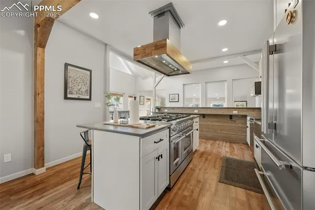 a kitchen with stainless steel appliances kitchen island granite countertop a table chairs sink and cabinets