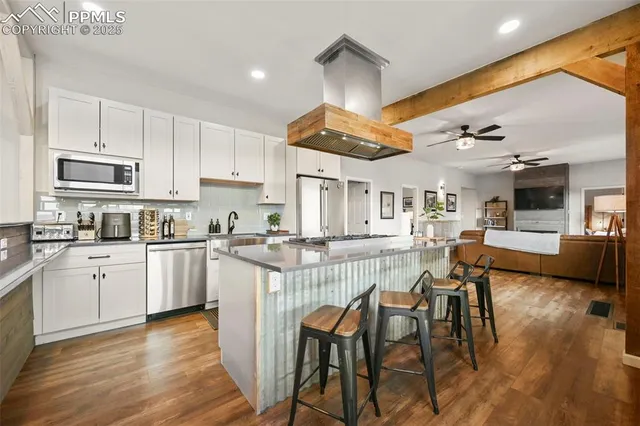 a large kitchen with stainless steel appliances granite countertop a lot of counter space and wooden floors