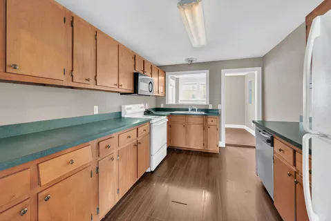 a kitchen with granite countertop white cabinets and white appliances