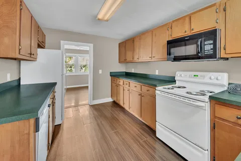 a kitchen with stainless steel appliances granite countertop a stove top oven a sink dishwasher and a microwave oven with wooden cabinets