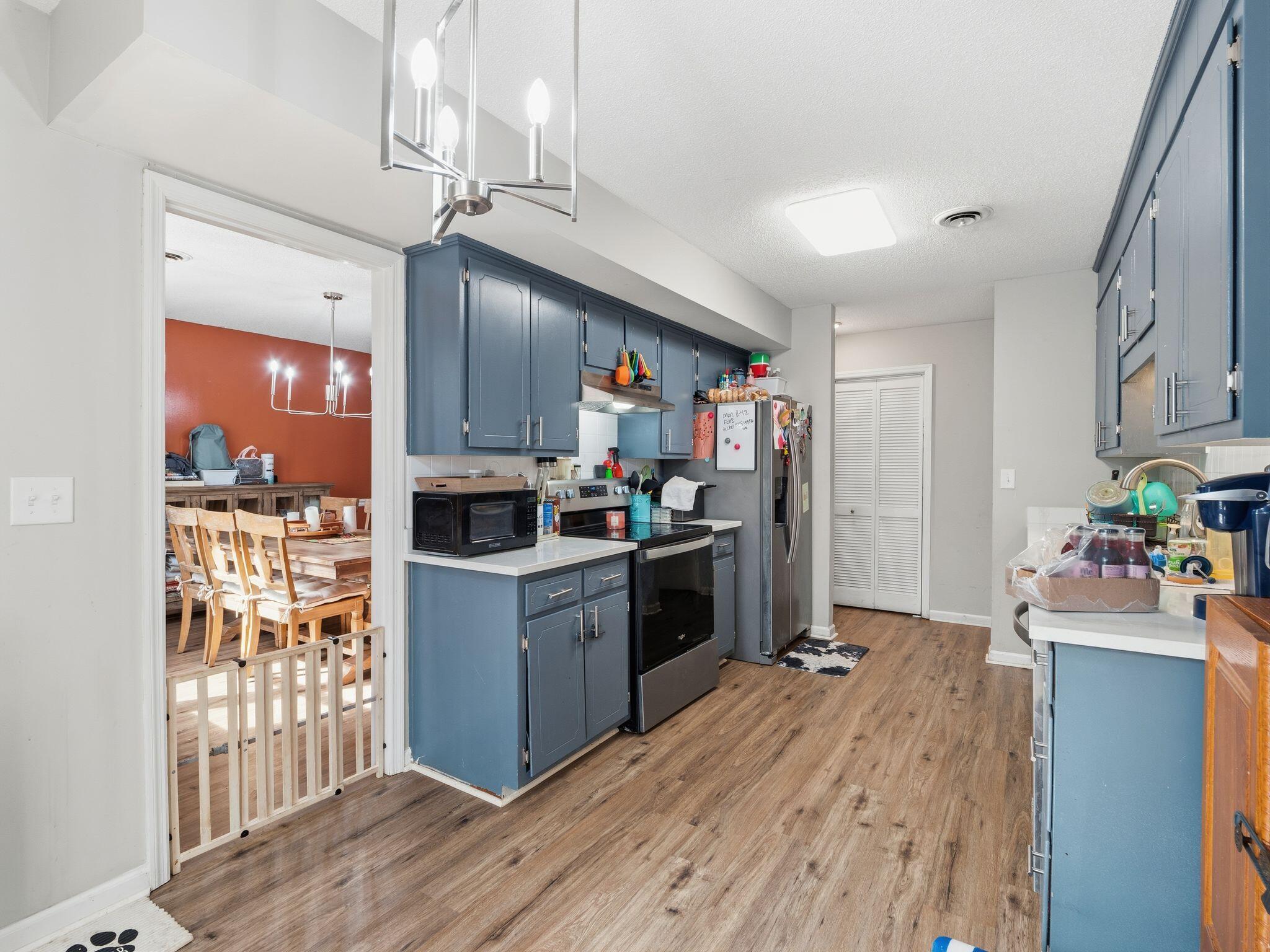 90 Fall Drive Collinsville, VA 24078 - Photo 10 of 22 a kitchen with stainless steel appliances kitchen island granite countertop a refrigerator a stove top oven a chimney wooden floor and cabinets