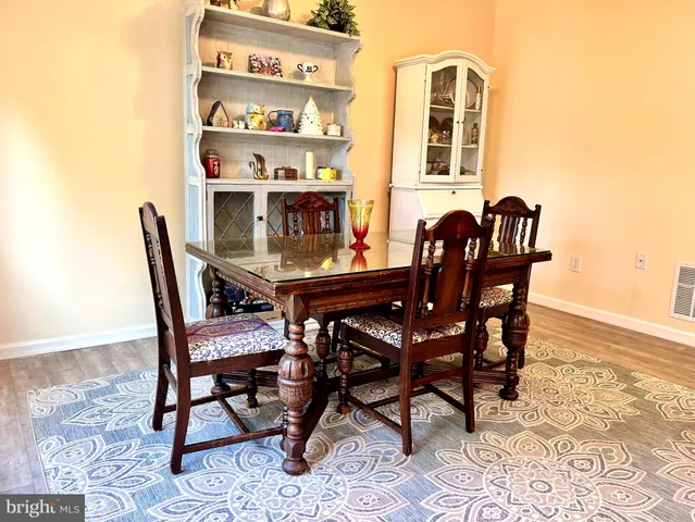 a kitchen with stainless steel appliances granite countertop a refrigerator a sink dishwasher a stove a dining table and chairs with wooden floor