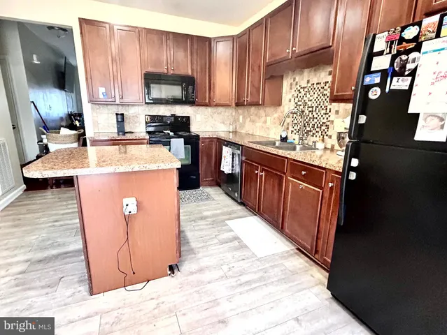 a kitchen with granite countertop wood cabinets stainless steel appliances and a counter space