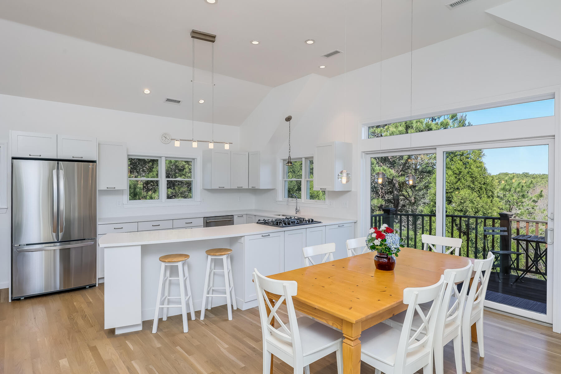 1075 3rd Avenue Wellfleet, MA 02667 - Photo 18 of 87 a kitchen with kitchen island a stove a refrigerator a dining table and chairs with wooden floor