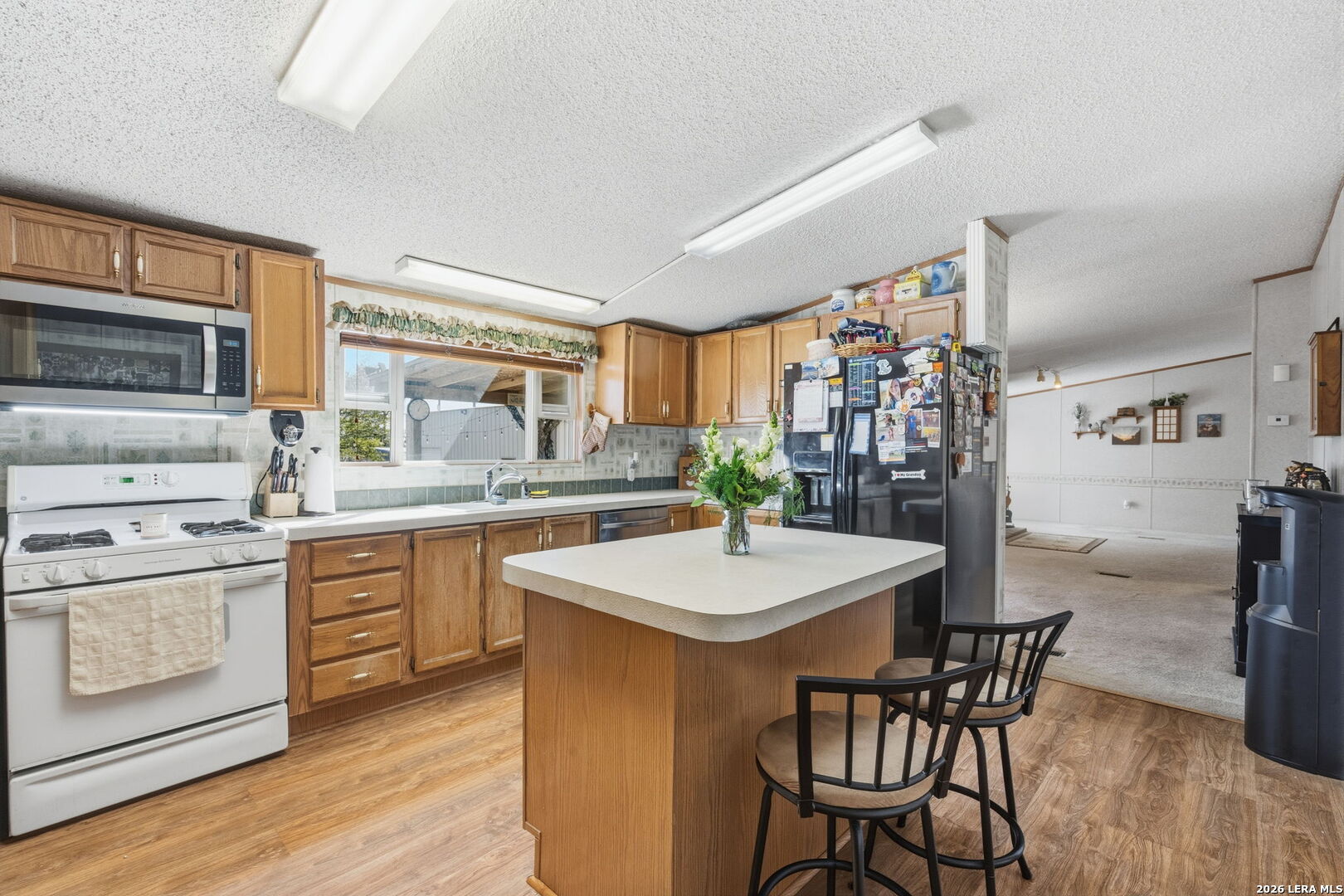 708 Mesquite Street Jourdanton, TX 78026 - Photo 15 of 49 a kitchen with stainless steel appliances granite countertop a stove a sink dishwasher and a refrigerator with wooden floor