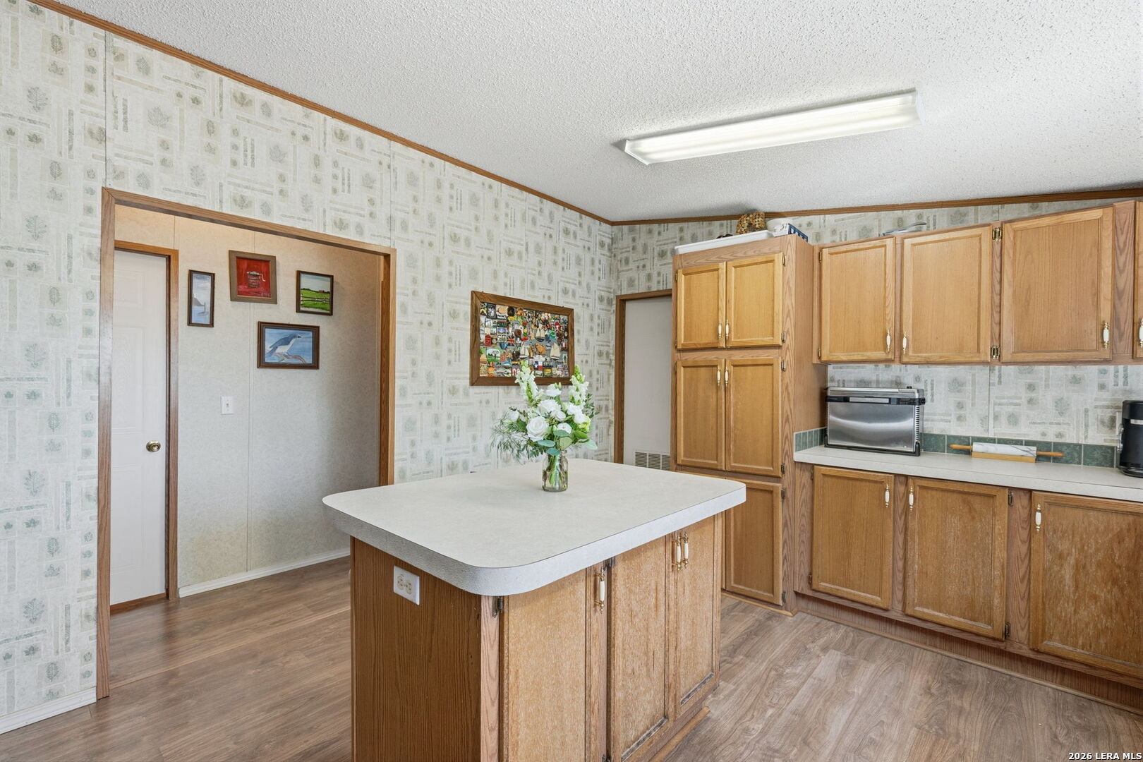 708 Mesquite Street Jourdanton, TX 78026 - Photo 16 of 49 a kitchen with stainless steel appliances granite countertop a refrigerator a sink dishwasher and white cabinets with wooden floor