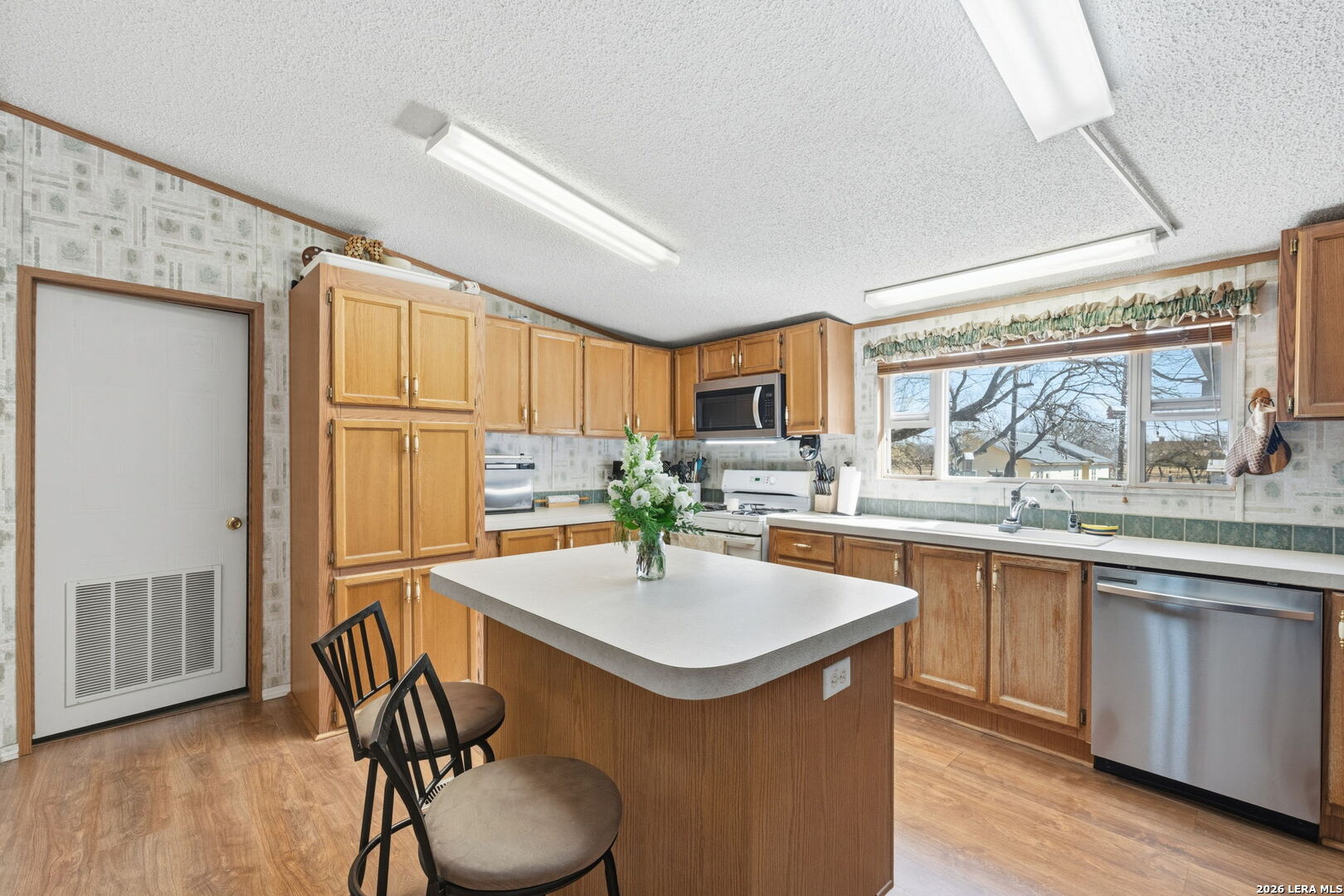 708 Mesquite Street Jourdanton, TX 78026 - Photo 6 of 49 a kitchen with granite countertop a sink stove and refrigerator