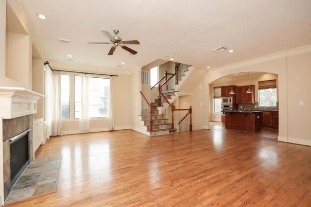 a view of an empty room and kitchen with fireplace wooden floor