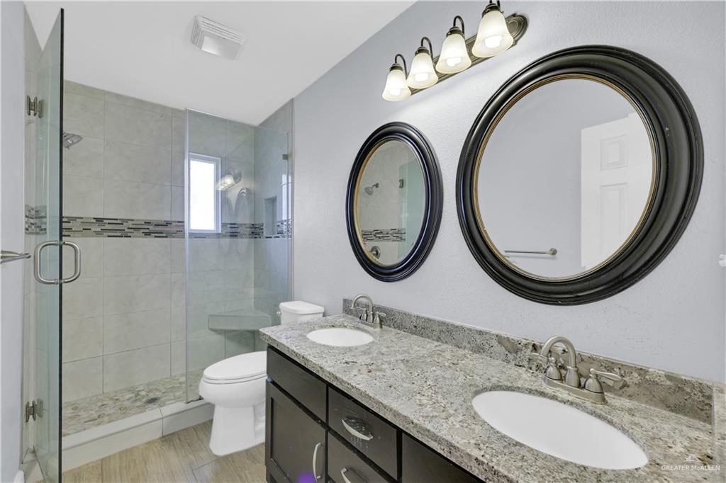 314 Santa Ana Avenue Rancho Viejo, TX 78575 - Photo 12 of 30 a bathroom with a granite countertop toilet a sink and a mirror