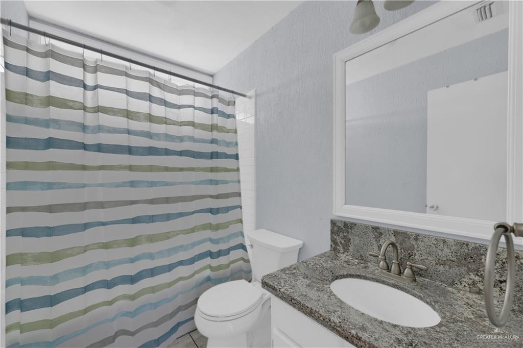 314 Santa Ana Avenue Rancho Viejo, TX 78575 - Photo 15 of 30 a bathroom with a granite countertop sink toilet and shower