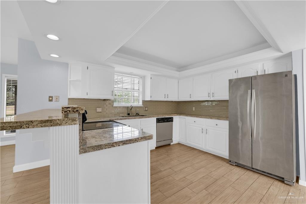 314 Santa Ana Avenue Rancho Viejo, TX 78575 - Photo 7 of 30 a kitchen with granite countertop a refrigerator and a stove top oven